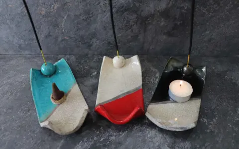 Tre porta incenso fai da te in ceramica, uno blu con cono, uno bianco e rosso, e uno nero con candela accesa.