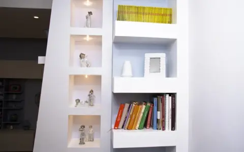 Moderne idee mensole in cartongesso con nicchie illuminate per statuette e ripiani per libri e decorazioni.