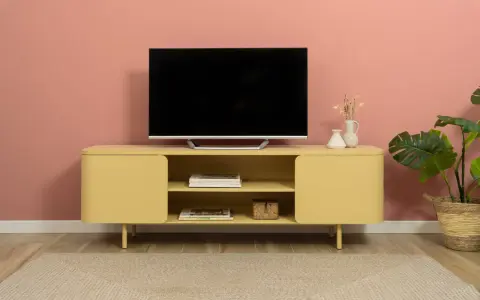 Un mobile giallo vivace con un televisore, riviste e vasi crea una parete tv particolare.
