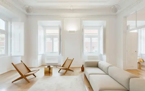 Soggiorno minimalista con divano chiaro, sedie in legno e tavolino dorato. Un esempio di come un consulente d'arredo può creare un ambiente luminoso e accogliente.