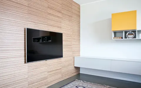 Pannellatura a righe per rivestire una parete interna in modo economico, con TV incassata e mensole moderne.