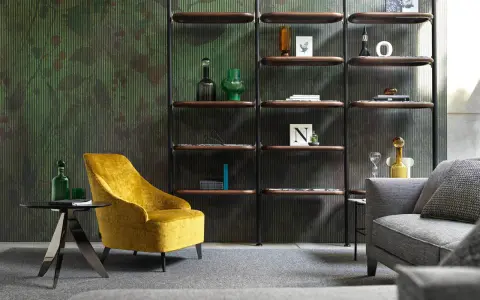 Un comodo angolo lettura con poltrona gialla, tavolino nero e libreria a parete con oggetti decorativi.