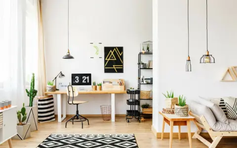 Un moderno angolo studio con scrivania in legno, computer, piante e un divano accogliente.