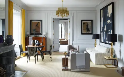 Elegante soggiorno in stile casa art deco con mobili di design, lampadario dorato e opere d'arte astratte.