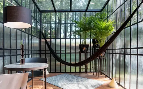 Veranda piccola arredata con amaca, piante e un tavolino. Idee per arredare una veranda piccola con stile e comfort.