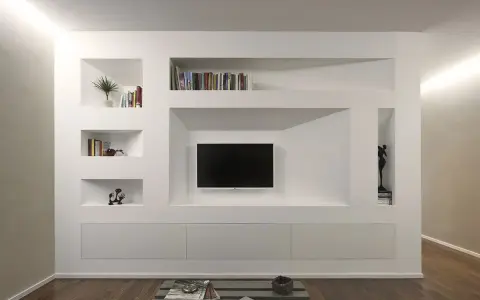 Una moderna parete in cartongesso con nicchie per libri, TV e decorazioni.