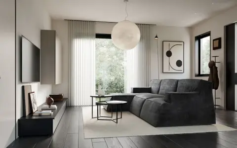 Soggiorno in una casa stile moderno contemporaneo, con divano angolare grigio, tavolini neri, TV a parete e grande lampada sferica.