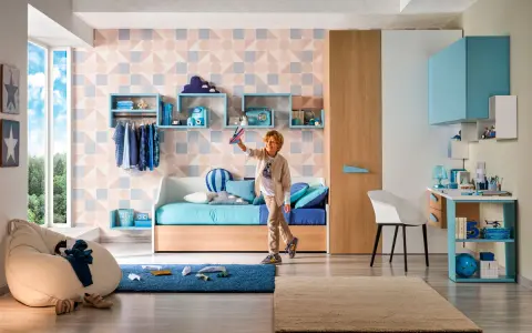 Ragazzo gioca con aeroplanino in cameretta. Ecco come sistemare i libri senza libreria: mensole a muro e contenitori colorati.