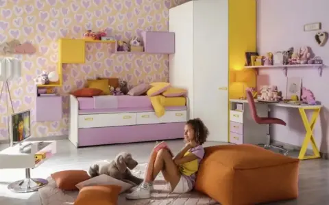 Cameretta bimba con carta da parati a cuori, letto estraibile, scrivania e armadio. Idee colorate e giocose per uno spazio da sogno.