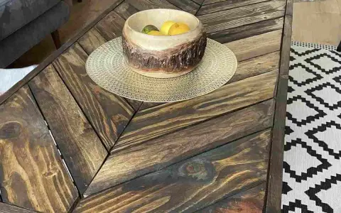 Tavolo con pallet fai da te, con un cesto di frutta in legno e un tappeto geometrico.