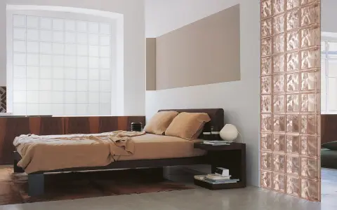 Camera da letto con letto marrone, un divisorio in **vetrocemento moderno** color rosa e una grande finestra in vetro opaco.