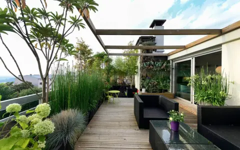 Un terrazzo moderno e accogliente, perfetto per arredare con stile. Mobili in rattan nero, un giardino verticale rigoglioso e piante verdi creano un'oasi urbana.