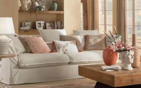 Divano bianco con cuscini decorati, lampada e tavolino in legno creano un'atmosfera di **stile cozy**.
