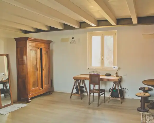 Arredamento casa di campagna: armadio antico in legno, specchio, scrivania rustica con sedia, tavolino rotondo e lampada a forma di Torre Eiffel.