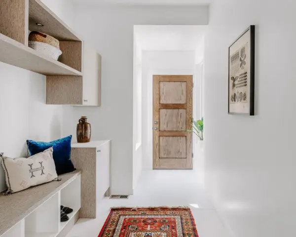 Ingresso accogliente con panca, cuscini e un tappeto persiano. Idee per decorazioni porte interne fai da te ispirate a questo stile.