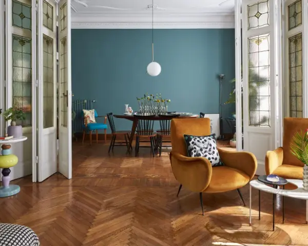 Salotto con poltrone ocra, tavolino dal design moderno e porte a soffietto con vetri decorati, un mix di stile vintage e contemporaneo.