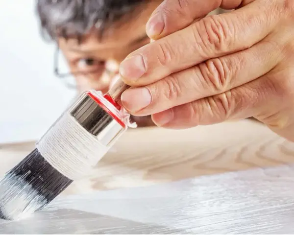 Mano applica primer per mdf con pennello. Preparazione per una finitura perfetta.