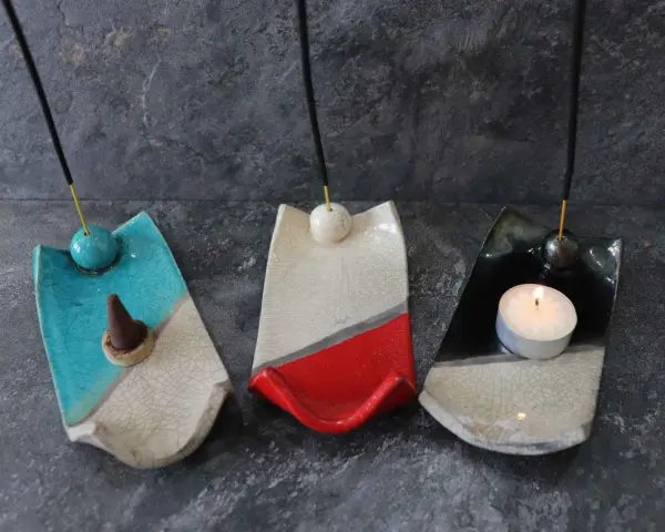 Tre porta incenso fai da te in ceramica, uno blu con cono, uno bianco e rosso, e uno nero con candela accesa.