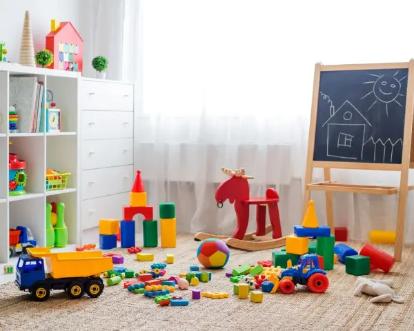 Un angolo pieno di giochi colorati, blocchi, un camioncino, un cavallo a dondolo e una lavagna: perfette idee stanza giochi bambini per stimolare la creatività.