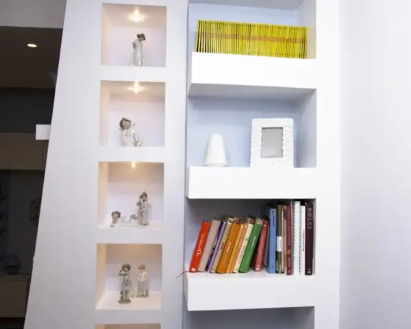 Moderne idee mensole in cartongesso con nicchie illuminate per statuette e ripiani per libri e decorazioni.