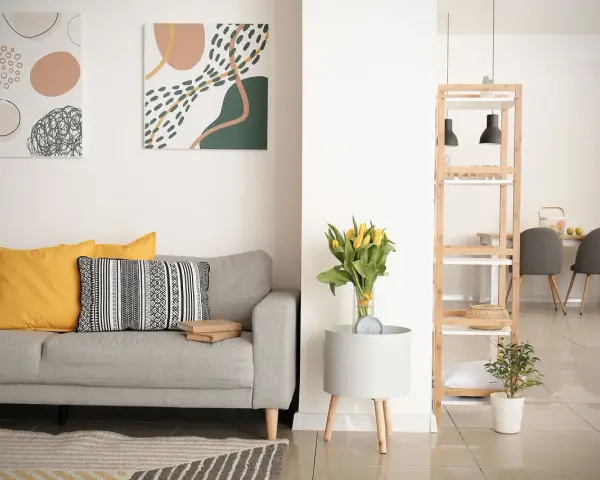 Soggiorno moderno con divano grigio, cuscini gialli e decorazioni astratte. Si nota la differenza tra ammobiliato e arredato: qui, ogni elemento è scelto con cura per creare un ambiente accogliente.