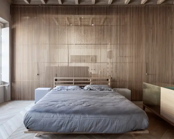 Camerette con separè in legno che creano un ambiente caldo e moderno. Letto matrimoniale con biancheria grigia e comodini bianchi.