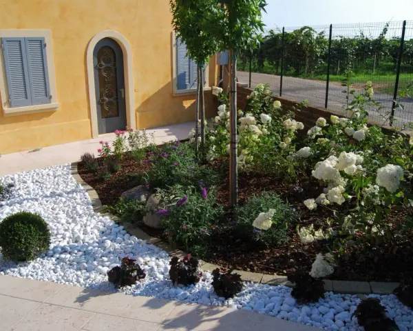Giardini idee da copiare: un angolo con ghiaia bianca, arbusti verdi e ortensie bianche.
