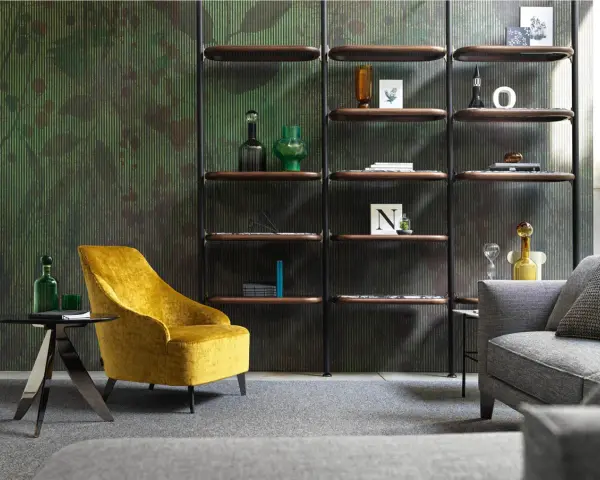 Un comodo angolo lettura con poltrona gialla, tavolino nero e libreria a parete con oggetti decorativi.