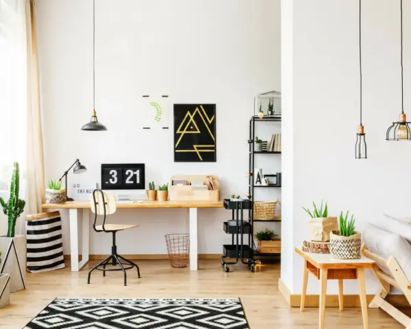 Un moderno angolo studio con scrivania in legno, computer, piante e un divano accogliente.