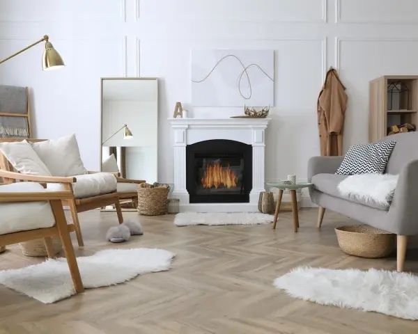 Un soggiorno accogliente con camino acceso, poltrone in legno, divano grigio e tappeti soffici. Perfetto per una casa cozy.