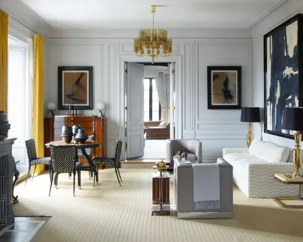 Elegante soggiorno in stile casa art deco con mobili di design, lampadario dorato e opere d'arte astratte.