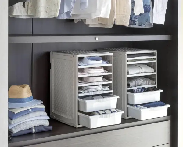Organizzazione armadio: camicie piegate in contenitori modulari, pile di vestiti e un cappello su una mensola.