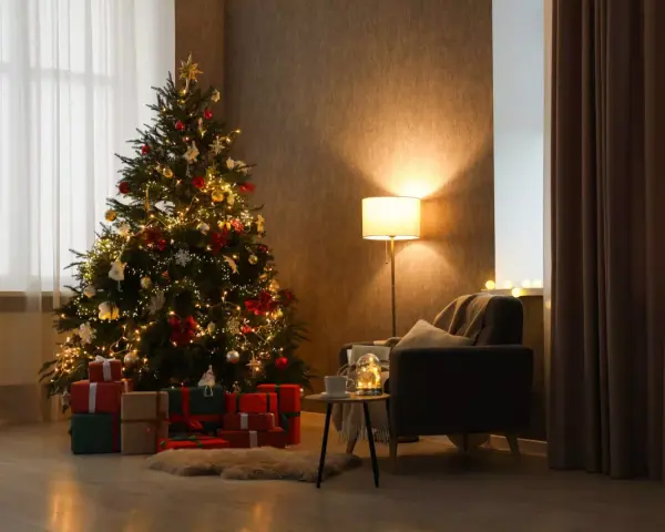 Un accogliente soggiorno con un **albero di Natale stile scandinavo** illuminato, circondato da regali. Una poltrona invitante e una lampada creano un'atmosfera calda.