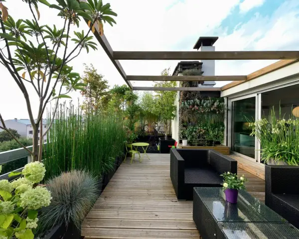 Un terrazzo moderno e accogliente, perfetto per arredare con stile. Mobili in rattan nero, un giardino verticale rigoglioso e piante verdi creano un'oasi urbana.