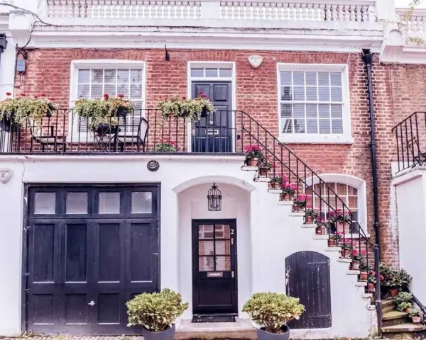 Idee case di campagna esterni: scala bianca fiorita, balcone con piante, porta scura e garage.