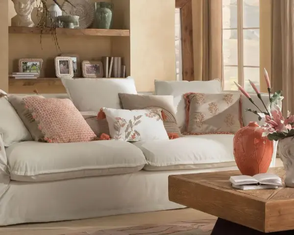 Divano bianco con cuscini decorati, lampada e tavolino in legno creano un'atmosfera di **stile cozy**.