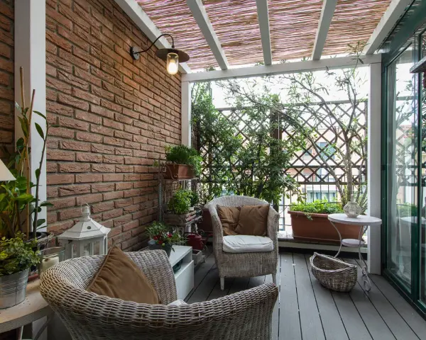 Accogliente veranda piccola con mobili in vimini, piante verdi e un pergolato in bambù. Perfetta per creare un angolo relax.