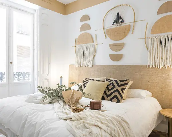 Accogliente camera da letto stile boho con decorazioni murali geometriche, tessuti naturali e un letto invitante.