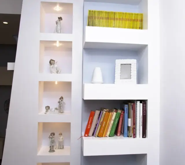 Moderne idee mensole in cartongesso con nicchie illuminate per statuette e ripiani per libri e decorazioni.