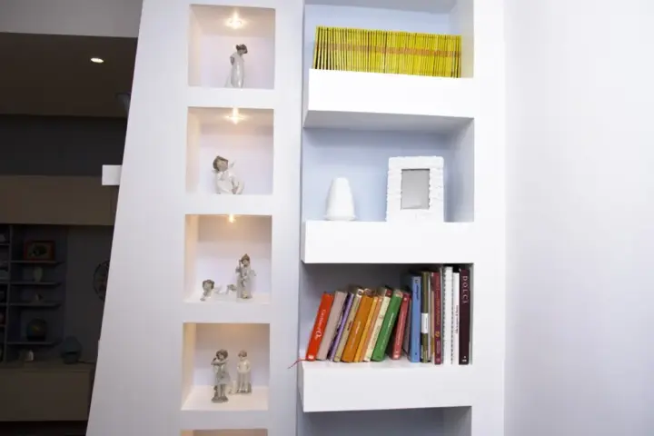 Moderne idee mensole in cartongesso con nicchie illuminate per statuette e ripiani per libri e decorazioni.