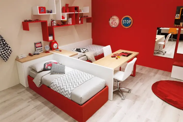 Soluzione creativa per come dividere cameretta maschio e femmina: due letti separati da una scrivania, con arredi a tema auto.