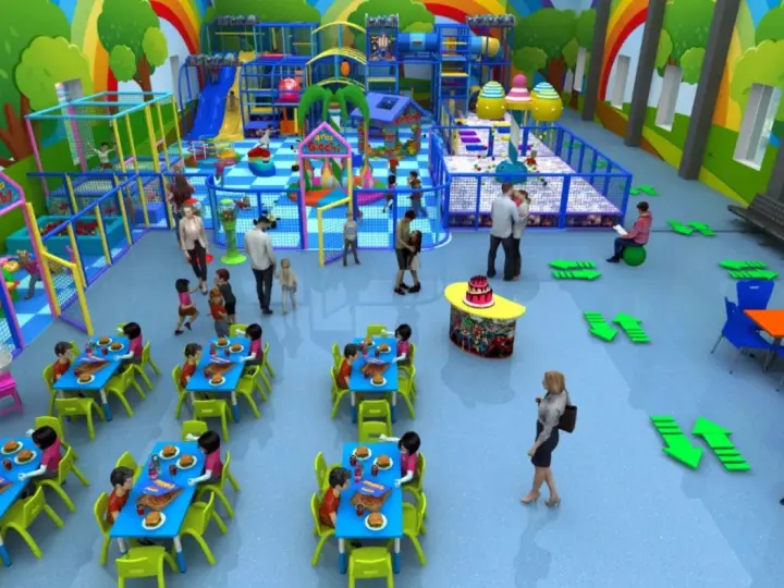Colorata sala giochi con scivoli, piscine di palline e tavoli apparecchiati per feste di compleanno. Bambini giocano e mangiano felici.