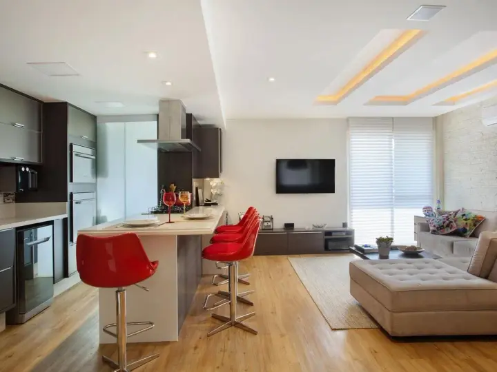 Elegante soggiorno con cucina a vista, illuminato da moderni controsoffitti in cartongesso.