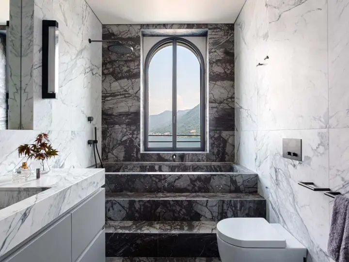 Bagno di lusso con vasca doccia in muratura, rivestimenti in marmo e vista panoramica.