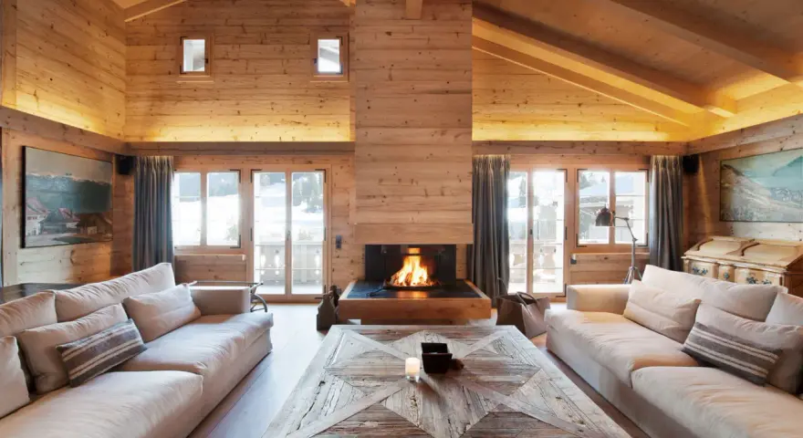 Un **soggiorno caldo e accogliente** con camino scoppiettante, divani comodi e soffitto in legno.