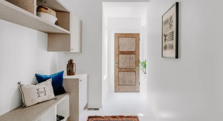 Ingresso accogliente con panca, cuscini e un tappeto persiano. Idee per decorazioni porte interne fai da te ispirate a questo stile.