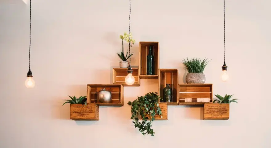 Come posizionare i cubi a muro: una composizione creativa con piante, bottiglie e decorazioni su mensole di legno.