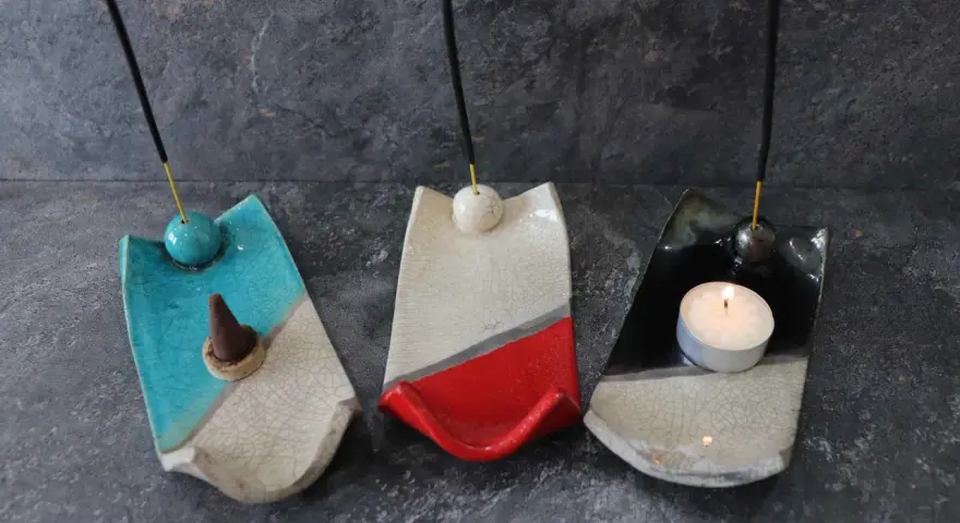 Tre porta incenso fai da te in ceramica, uno blu con cono, uno bianco e rosso, e uno nero con candela accesa.