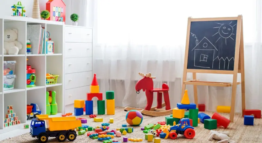 Un angolo pieno di giochi colorati, blocchi, un camioncino, un cavallo a dondolo e una lavagna: perfette idee stanza giochi bambini per stimolare la creatività.