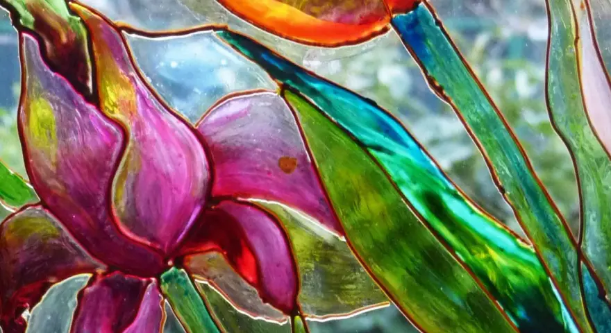 Dettaglio di un fiore dipinto su vetro, con petali viola e verdi vibranti. Un'ispirazione per il **dipinto su vetro fai da te**.
